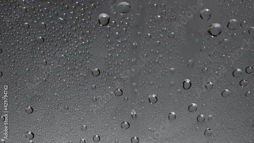 Video of rain and water droplets flowing through clear glass and rain sounds.