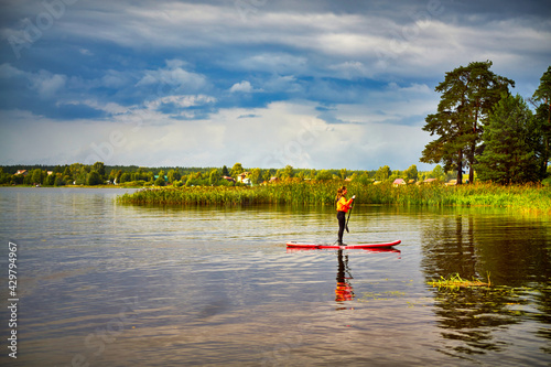 A girl is riding a subsurf on a wide river in cloudy weather. photo