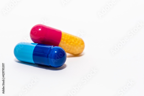 Close-up colorful powder soft capsules pill isolated on white. blue pink yellow medicine supplement vitamin