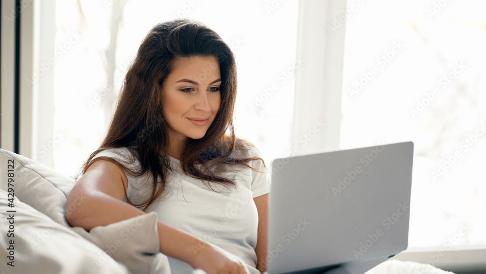 Young woman of European appearance online training on a laptop. Makes online purchases on the computer. Housewife blogger sits at home. Young woman of European appearance online training on a laptop. Makes online purchases on the computer. Housewife blogger sits at home.