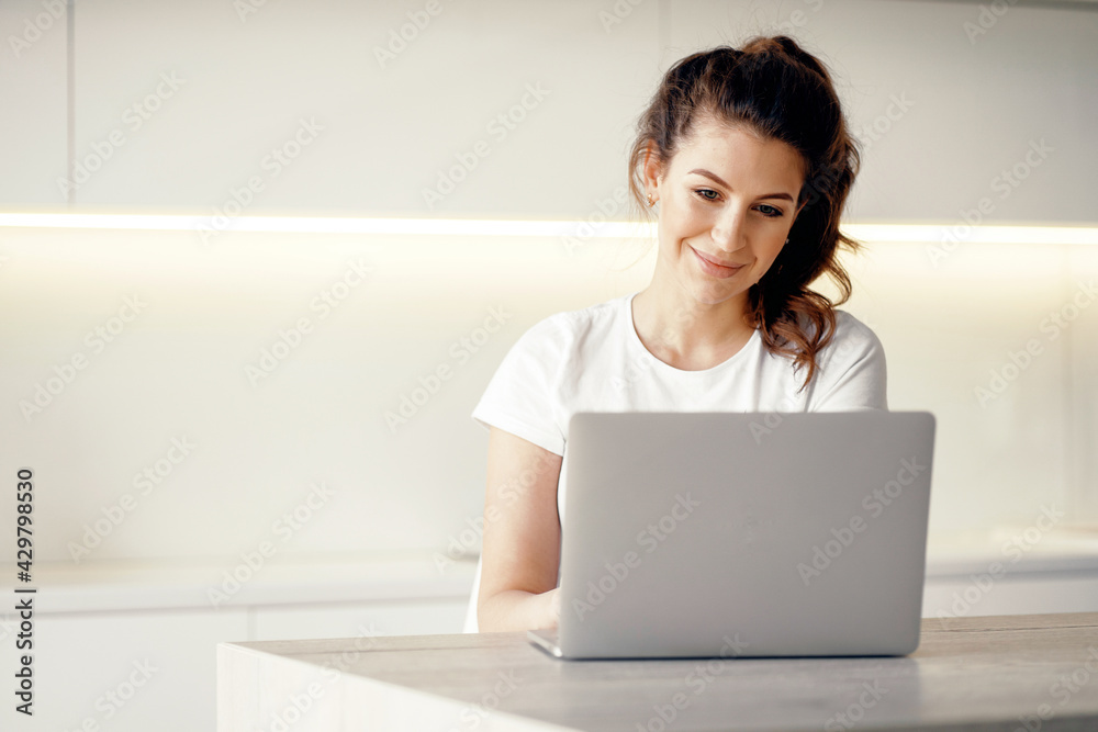 Does work on a new project remotely. Portrait of a woman sitting at home and typing on a computer text. Orders clothes online at home. A brunette of European appearance. Does work on a new project remotely. Portrait of a woman sitting at home and typing on a computer text. Orders clothes online at home. A brunette of European appearance.