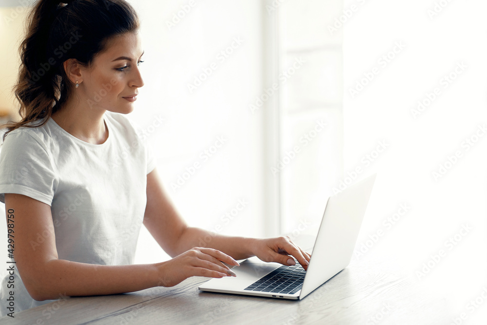 Orders online purchases in the apartment. A brunette of European appearance. Does work on a new project remotely. Portrait of a woman sitting at home and typing on a computer text. Orders online purchases in the apartment. A brunette of European appearance. Does work on a new project remotely. Portrait of a woman sitting at home and typing on a computer text.