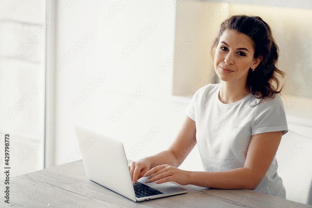 A brunette of European appearance. Does work on a new project remotely. Orders online purchases in the apartment. Portrait of a woman sitting at home and typing on a computer text. A brunette of European appearance. Does work on a new project remotely. Orders online purchases in the apartment. Portrait of a woman sitting at home and typing on a computer text.