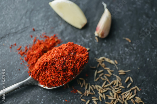 The spices are shot with a strong shot. Red pepper on a teaspoon, close-up, garlic, onion