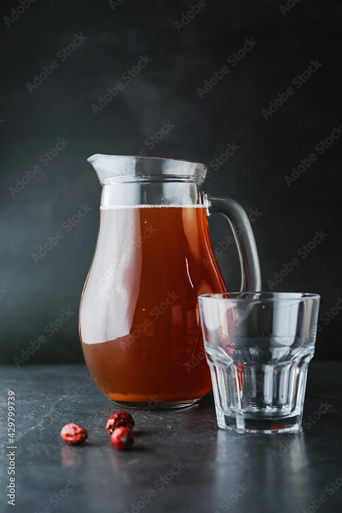 Delicious healthy rosehip drink in a glass decanter on a dark background. Brown apricot juice or cocktail Delicious healthy rosehip drink in a glass decanter on a dark background. Brown apricot juice or cocktail