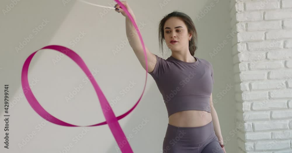 Beautiful caucasian gymnast performs with a pink ribbon. Elegant female athlete looking at camera during training - sports 4k footage Beautiful caucasian gymnast performs with a pink ribbon. Elegant female athlete looking at camera during training - sports 4k footage