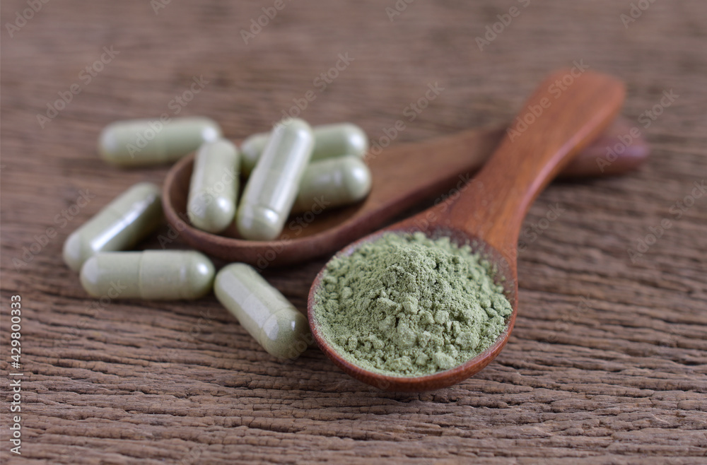 Andrographis paniculata powder and capsule
 (Herbal capsules) on a wooden background.
