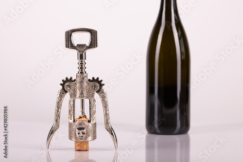 Red wine bottle, cork stopper and an italian prestigious corkscrew on a white background