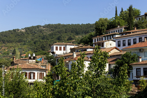 View of trees and old, historical, traditional houses in famous, touristic Aegean mountain village called "Sirince" in Izmir, Turkey. It is a sunny summer day. © theendup