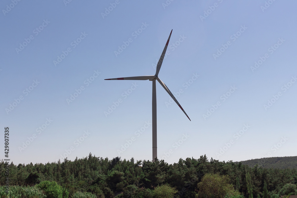 View of windmill farm and Aegean landscape in Urla district of Izmir province of Turkey. Wind power turbines produce clean, renewable energy. Sustainability concept. It is a sunny summer day. View of windmill farm and Aegean landscape in Urla district of Izmir province of Turkey. Wind power turbines produce clean, renewable energy. Sustainability concept. It is a sunny summer day.
