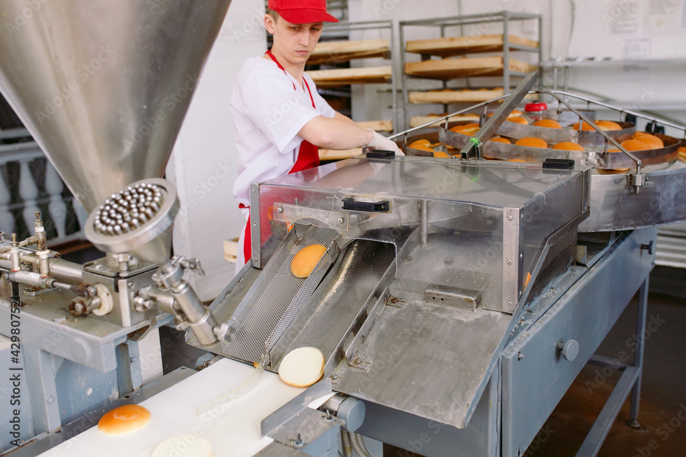 Conveyor belt in a bakery with newly baked buns. Conveyor belt in a bakery with newly baked buns.