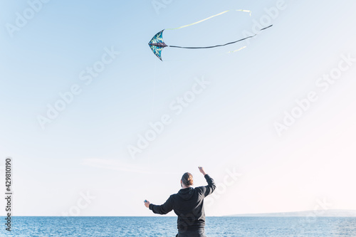 Obraz na płótnie Caucasian man with long hair and beard flying a kite by the sea on a beach in Portals. Palma de Mallorca, Spain (Copyspace) w salonie