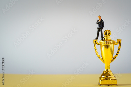 miniture businessman on gold Trophies on white background