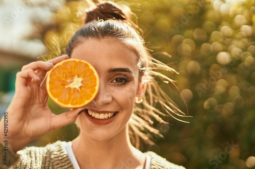 Beautiful brunette woman smiling happy with half orange over eye photo