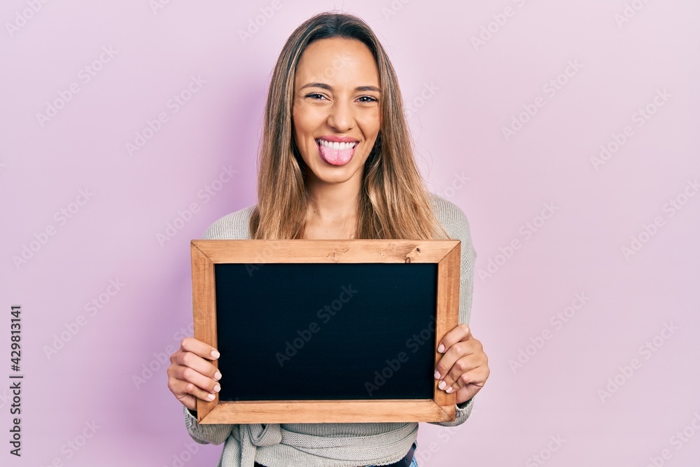 custom made wallpaper toronto digitalBeautiful hispanic woman holding small blackboard sticking tongue out happy with funny expression.