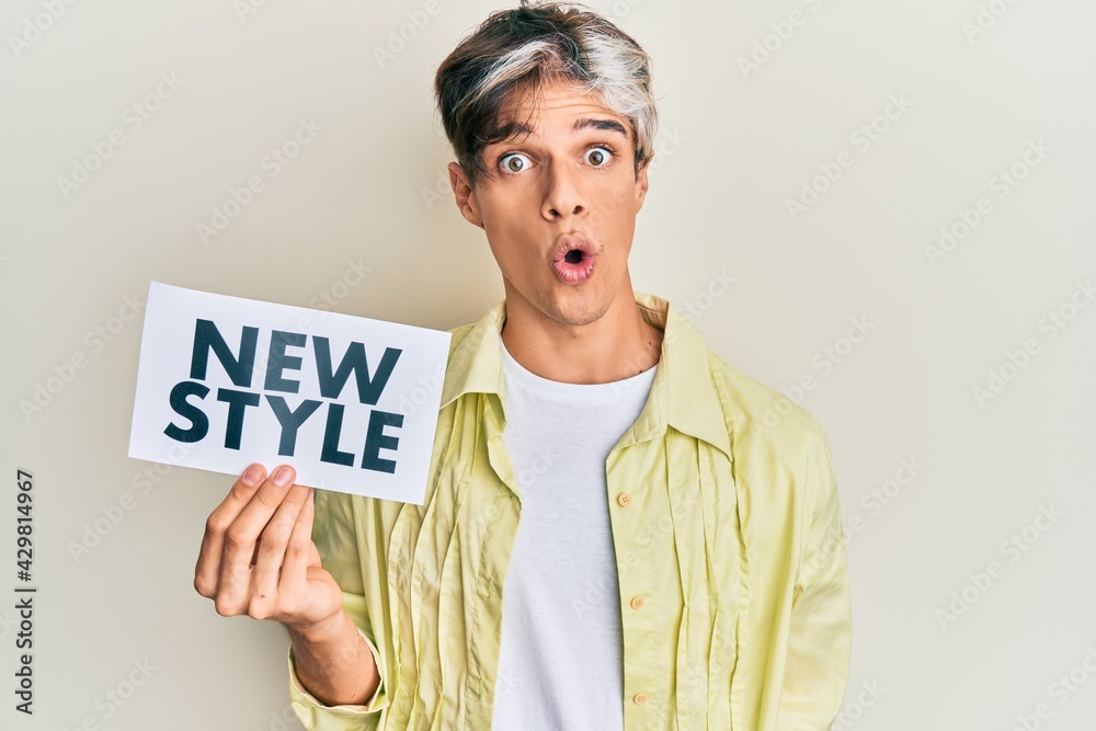 Young hispanic man holding new style message on paper scared and amazed with open mouth for surprise, disbelief face Young hispanic man holding new style message on paper scared and amazed with open mouth for surprise, disbelief face