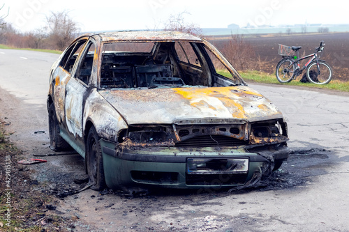 Burned car after an accident on the asphalt road. Front view. Arson of a car, criminal showdowns