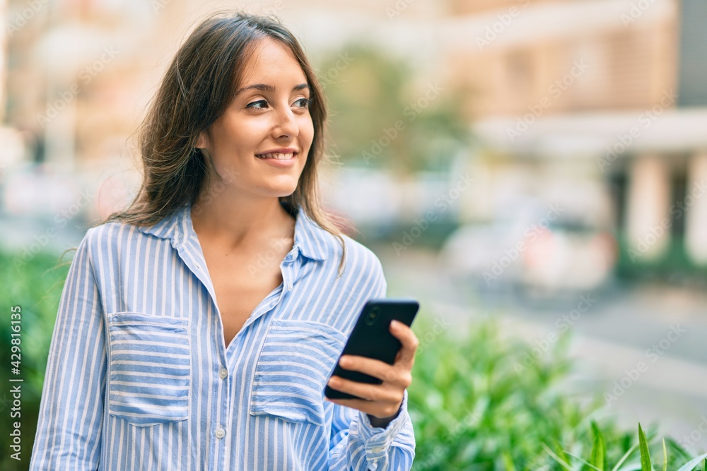 Young hispanic woman smiling happy using smartphone at the city. Young hispanic woman smiling happy using smartphone at the city.
