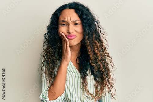 Young latin woman wearing casual clothes touching mouth with hand with painful expression because of toothache or dental illness on teeth. dentist