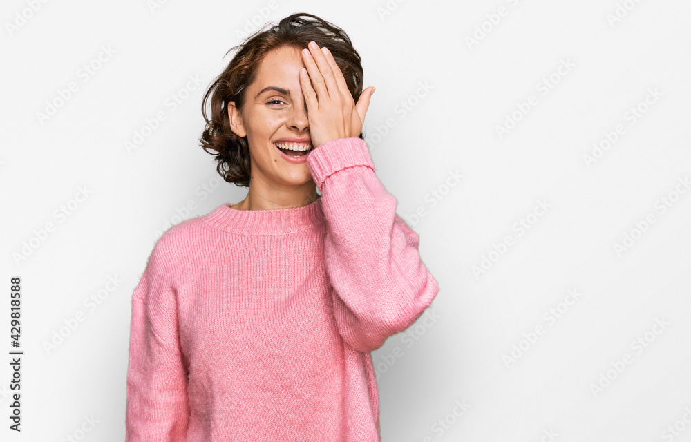 Young hispanic woman wearing casual clothes covering one eye with hand, confident smile on face and surprise emotion. Young hispanic woman wearing casual clothes covering one eye with hand, confident smile on face and surprise emotion.
