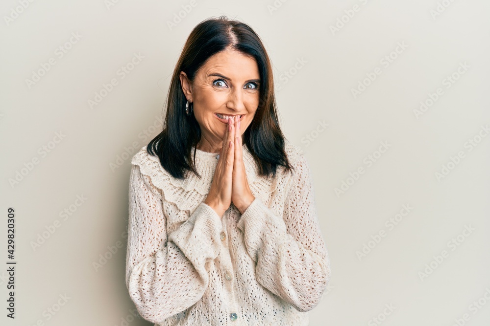 Middle age brunette woman wearing casual clothes praying with hands together asking for forgiveness smiling confident. Middle age brunette woman wearing casual clothes praying with hands together asking for forgiveness smiling confident.