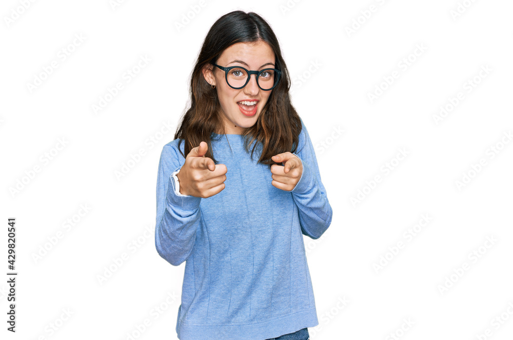 Young beautiful woman wearing casual clothes and glasses pointing fingers to camera with happy and funny face. good energy and vibes. Young beautiful woman wearing casual clothes and glasses pointing fingers to camera with happy and funny face. good energy and vibes.