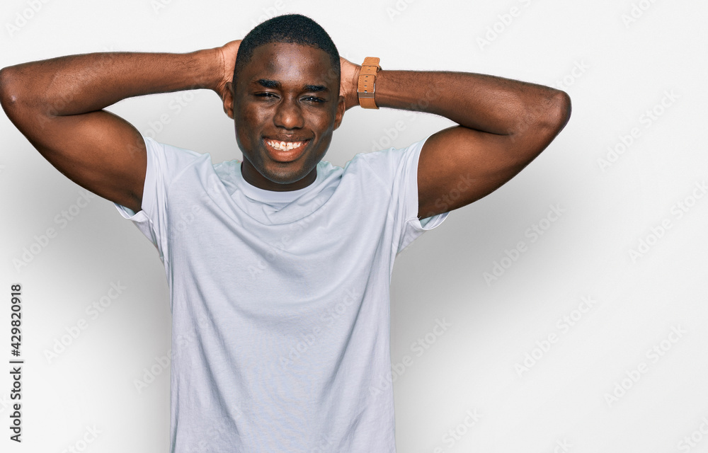 Young african american man wearing casual white t shirt relaxing and  stretching, arms and hands behind head and neck smiling happy Stock Photo |  Adobe Stock