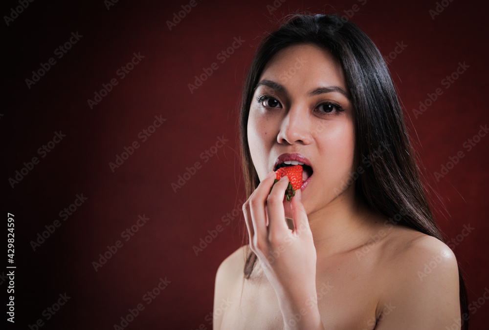 Young pretty woman bites into a strawberry - studio photography Young pretty woman bites into a strawberry - studio photography