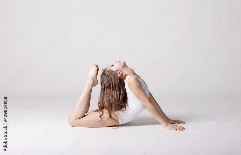 preteen girl gymnast trains on white background in white leotard. children's professional sports. rhythmic gymnastics. preteen girl gymnast trains on white background in white leotard. children's professional sports. rhythmic gymnastics.
