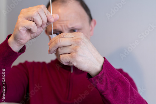 Man using a Covid-19 Rapid Lateral Flow Test placing a swab in an extraction tube