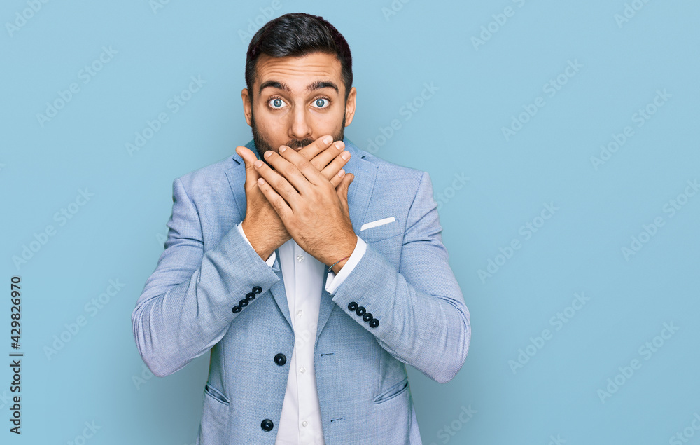 Young hispanic man wearing business jacket shocked covering mouth with hands for mistake. secret concept. Young hispanic man wearing business jacket shocked covering mouth with hands for mistake. secret concept.
