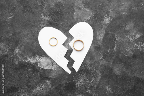 Broken paper heart with rings on grunge background