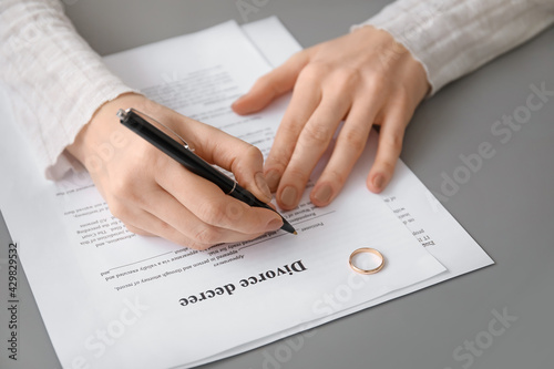 Woman signing decree of divorce at table, closeup