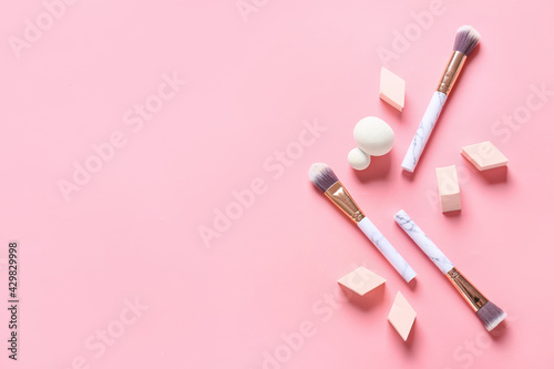 Makeup sponges with brushes on color background