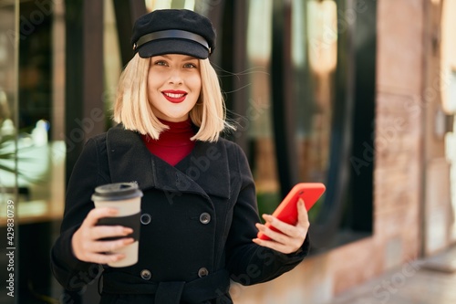 Young blonde woman using smartphone drinking coffee at the city.