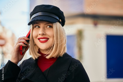 Young blonde woman smiling happy talking on the smartphone at the city.