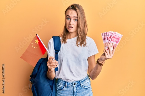 Photography Beautiful blonde woman exchange student holding china flag and yuan banknotes clueless and confused expression