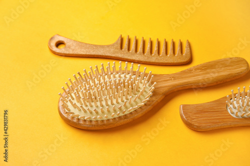 Wooden hair comb and brushes on color background