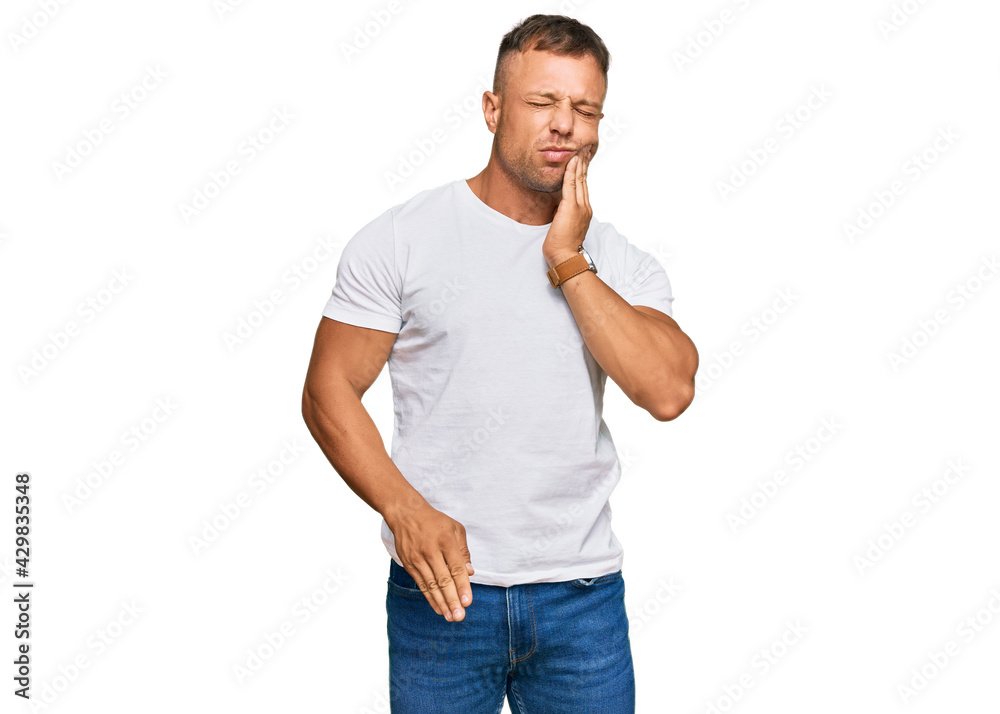 Fototapeta premium Handsome muscle man wearing casual white tshirt touching mouth with hand with painful expression because of toothache or dental illness on teeth. dentist