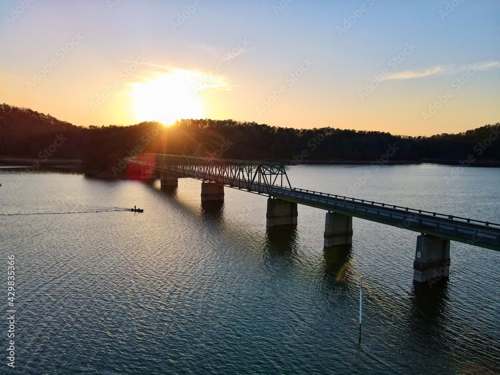 Bridge over the lake at sunset with a boat passing under