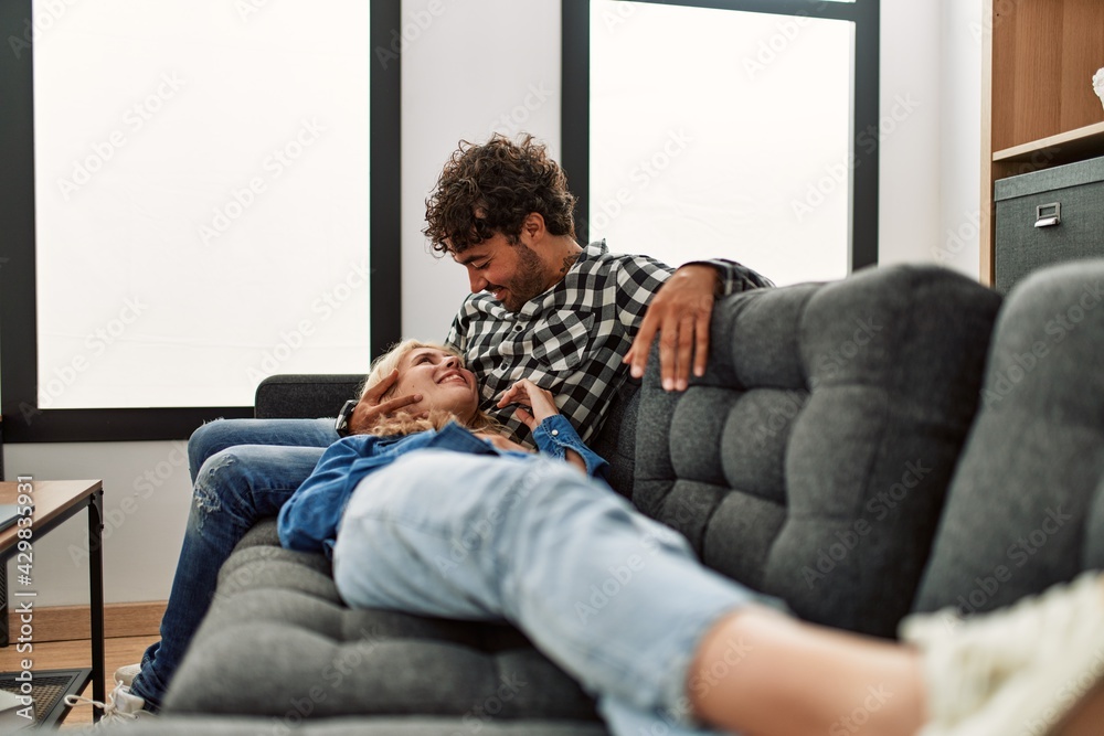 Young couple smling happy sitting on the sofa at home.