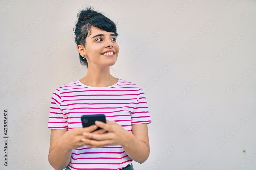 Young hispanic girl smiling happy using smartphone at the city. Young hispanic girl smiling happy using smartphone at the city.