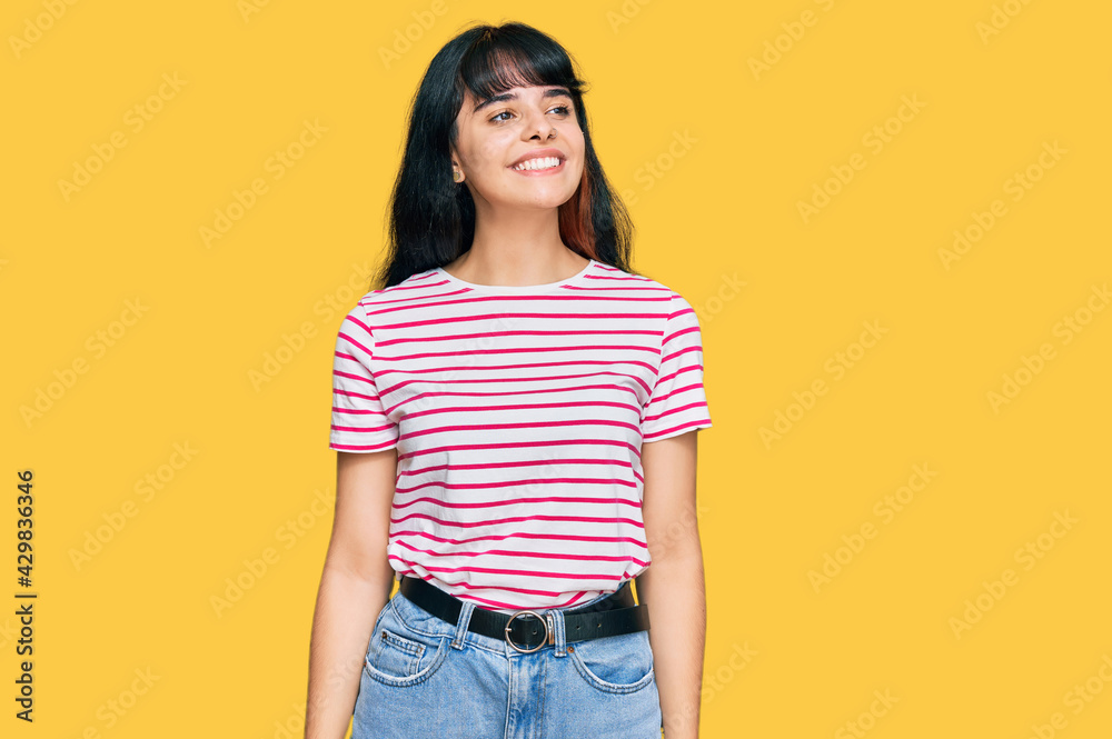 Young hispanic girl wearing casual clothes looking away to side with smile on face, natural expression. laughing confident. Young hispanic girl wearing casual clothes looking away to side with smile on face, natural expression. laughing confident.