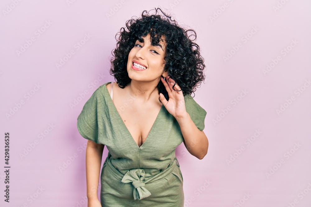 Young middle east woman wearing casual clothes smiling with hand over ear listening an hearing to rumor or gossip. deafness concept. Young middle east woman wearing casual clothes smiling with hand over ear listening an hearing to rumor or gossip. deafness concept.