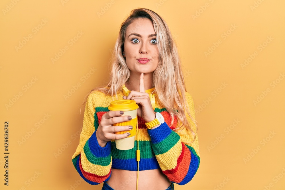 Beautiful young blonde woman drinking cup of coffee wearing headphones thinking concentrated about doubt with finger on chin and looking up wondering Beautiful young blonde woman drinking cup of coffee wearing headphones thinking concentrated about doubt with finger on chin and looking up wondering