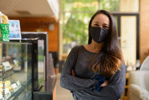 Portrait of confident woman wearing face mask for protection against coronavirus Covid-19 at restaurant