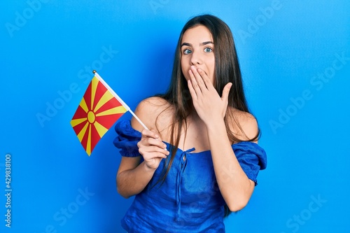 Cuadro en lienzo Young brunette teenager holding macedonian flag covering mouth with hand, shocked and afraid for mistake