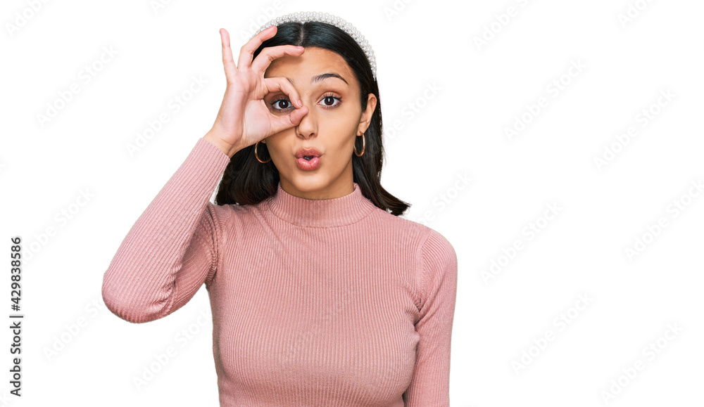Young hispanic girl wearing casual clothes doing ok gesture shocked with surprised face, eye looking through fingers. unbelieving expression. Young hispanic girl wearing casual clothes doing ok gesture shocked with surprised face, eye looking through fingers. unbelieving expression.