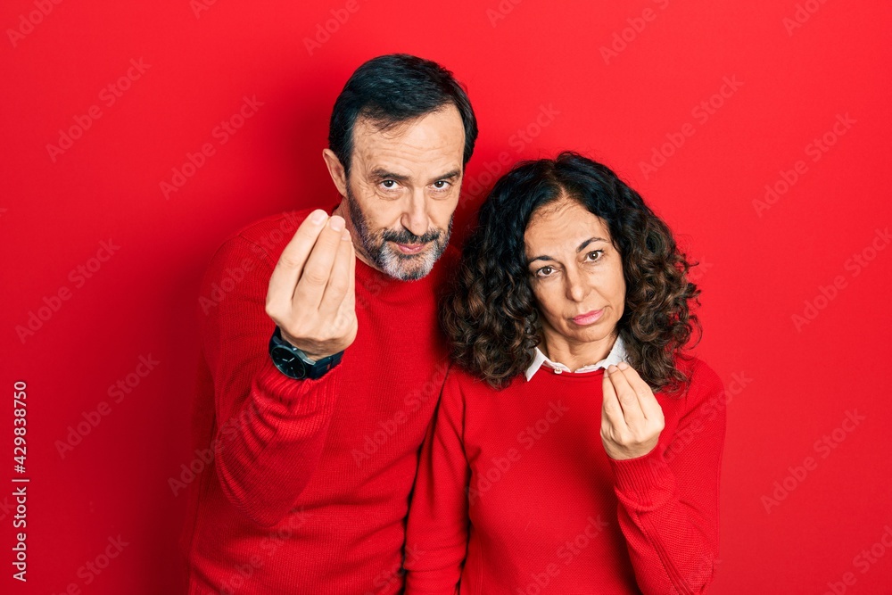 Middle age couple of hispanic woman and man hugging and standing together doing italian gesture with hand and fingers confident expression Middle age couple of hispanic woman and man hugging and standing together doing italian gesture with hand and fingers confident expression