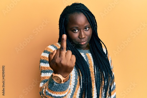 Young black woman with braids wearing casual winter sweater showing middle finger, impolite and rude fuck off expression